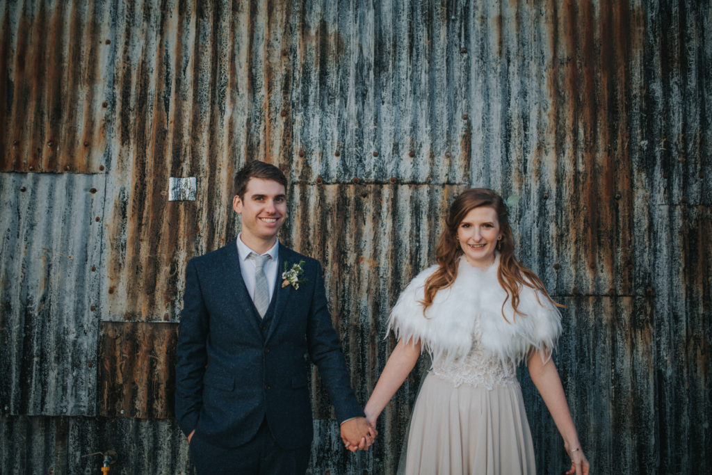 bride and groom in front of corrugated iron at Cripps Stone Barn