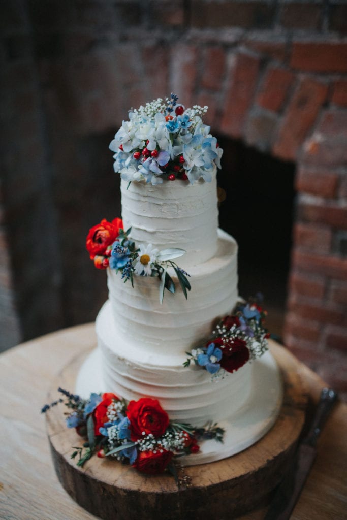 natural cake with white frosting and colourful wild flowers 
