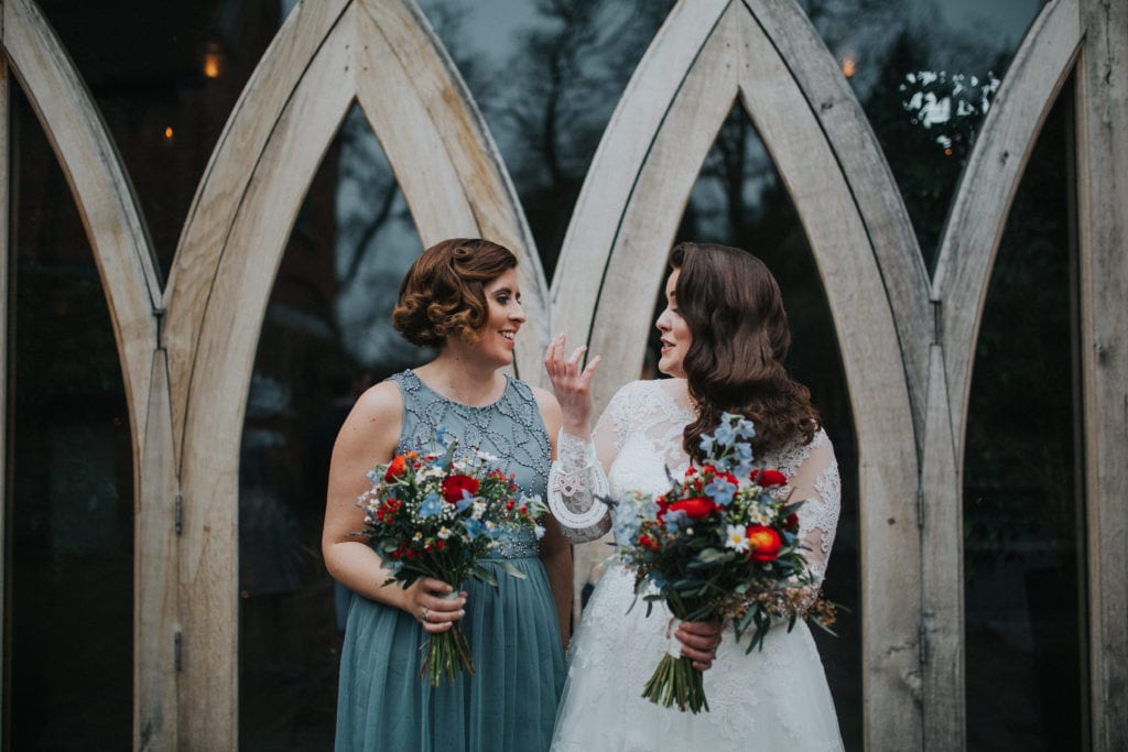 bride and sister in front of rustic doors 