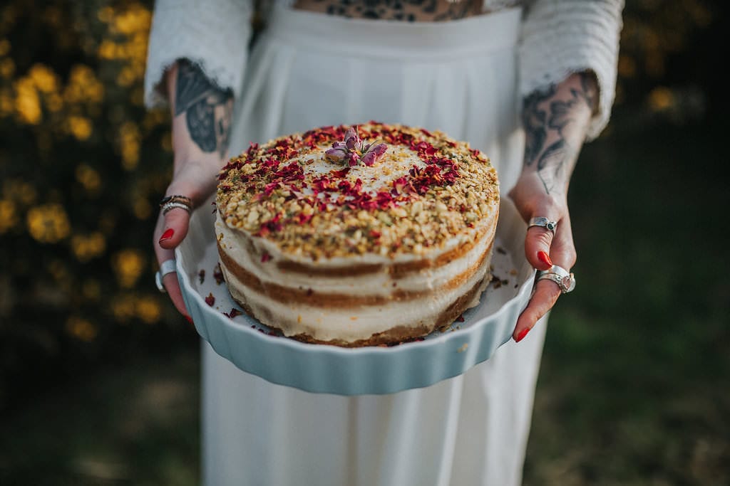 tattooed bride holding naked wedding cake