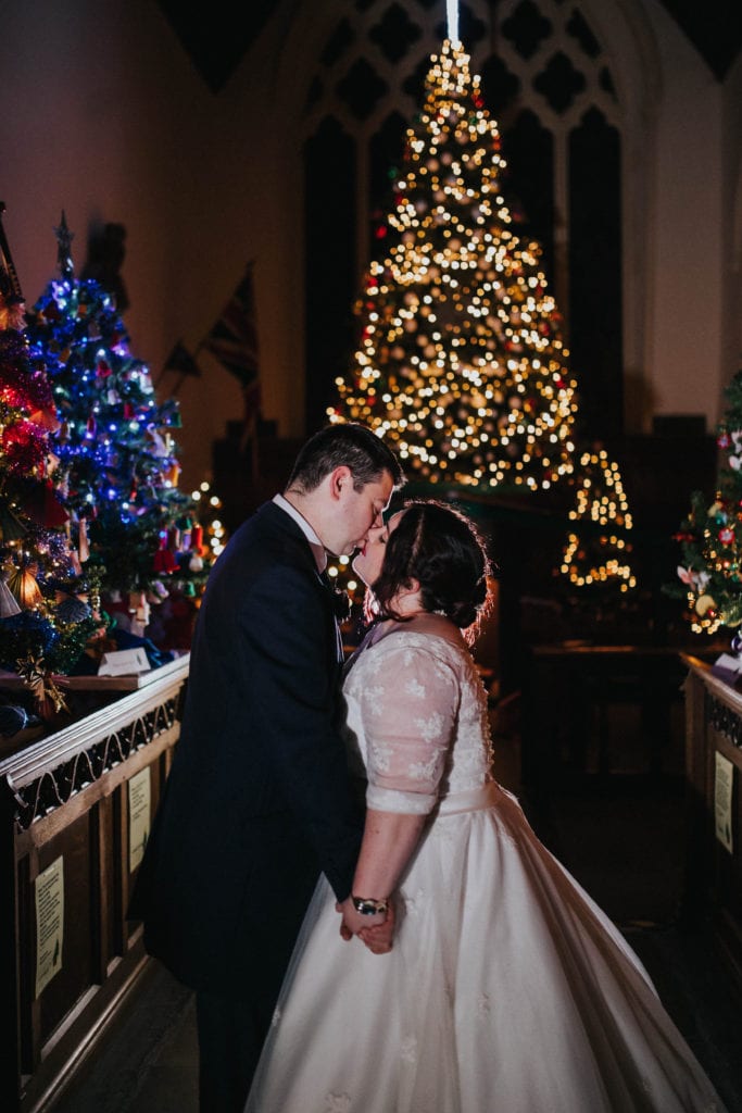 wedding couple in front of Christmas trees