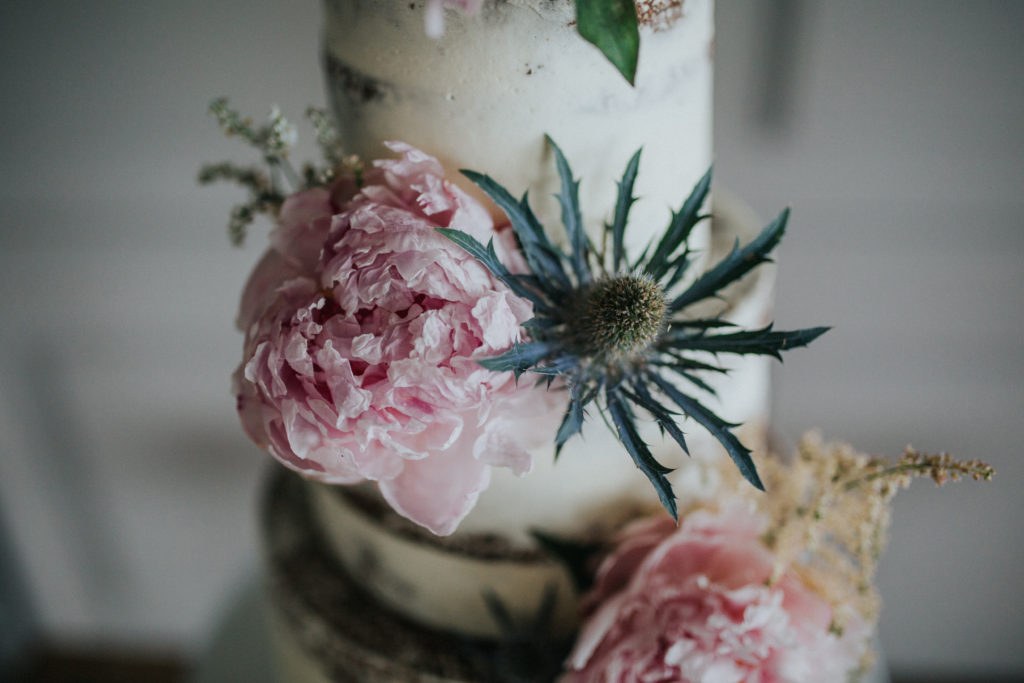naked cake with peony and thistle flowers