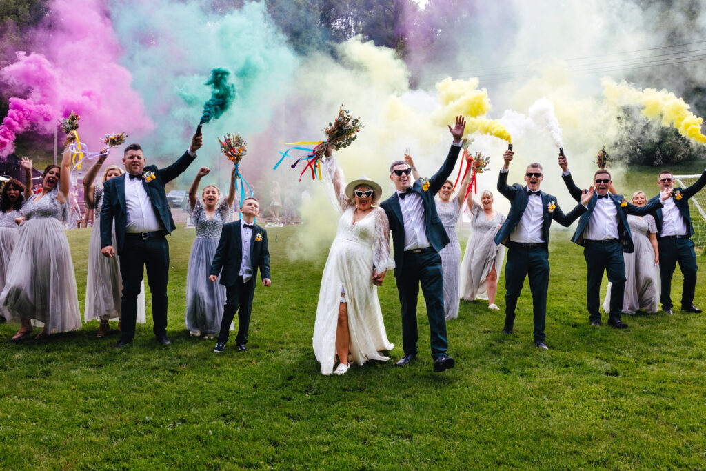 Bridal party photographed with colourful smoke bombs at Rhys Farm during festival wedding